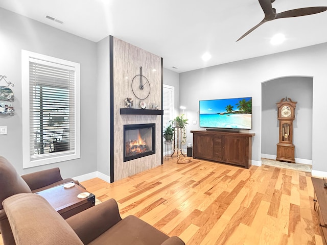 living room featuring visible vents, a fireplace, baseboards, and wood finished floors