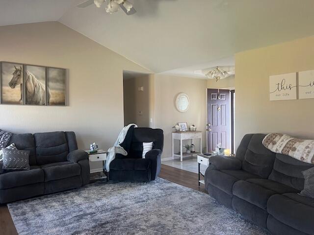 living room with a ceiling fan, vaulted ceiling, and wood finished floors