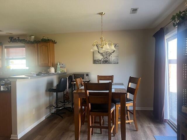 dining area with visible vents, a notable chandelier, baseboards, and wood finished floors