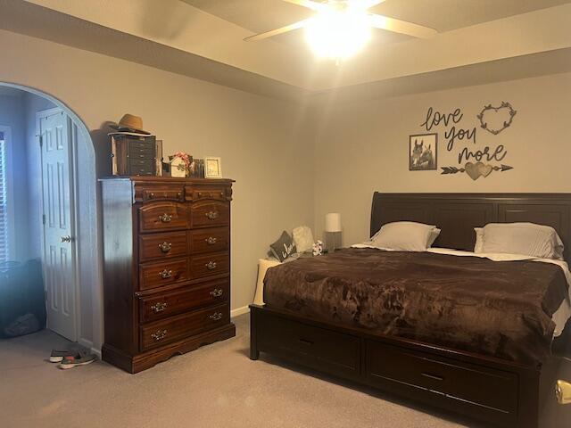 bedroom with arched walkways, light carpet, and a ceiling fan