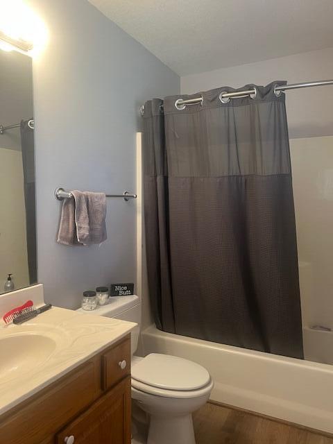 full bath with toilet, shower / bathtub combination with curtain, vanity, and wood finished floors