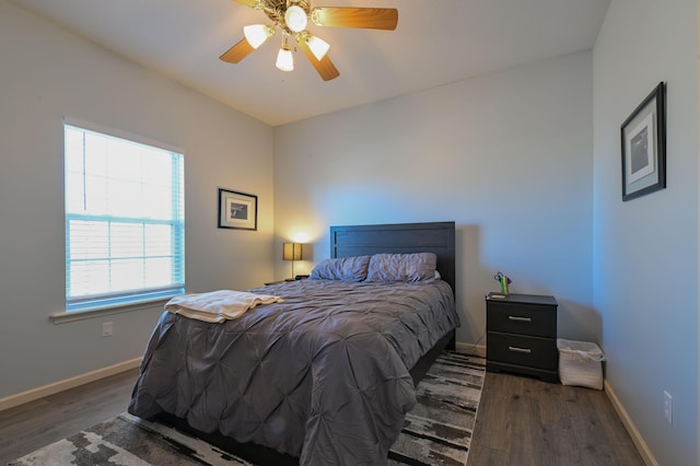 bedroom featuring ceiling fan, baseboards, and wood finished floors