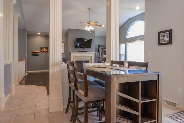 dining space featuring light tile patterned floors, a tile fireplace, visible vents, a ceiling fan, and vaulted ceiling