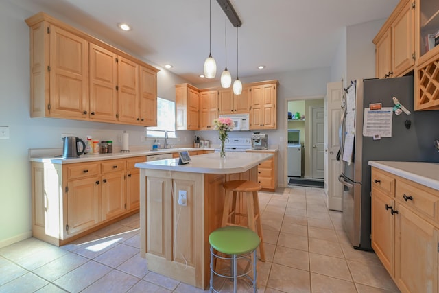 kitchen featuring white microwave, freestanding refrigerator, and light brown cabinetry