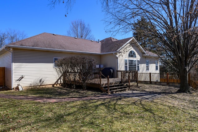 rear view of house featuring a shingled roof, fence, a lawn, and a wooden deck