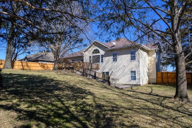 view of side of home featuring a fenced backyard, a lawn, and a deck