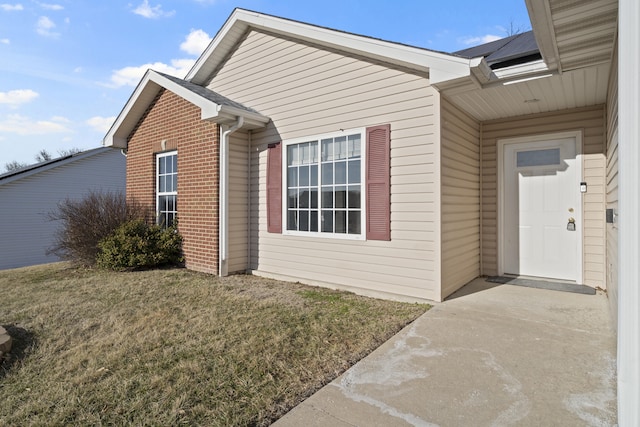 view of side of home featuring brick siding and a yard