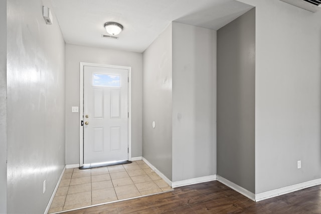 doorway with visible vents, baseboards, and wood finished floors