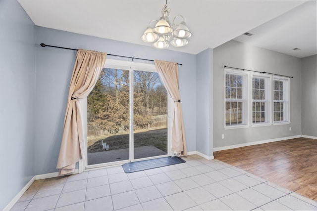 unfurnished dining area with an inviting chandelier, tile patterned floors, and baseboards