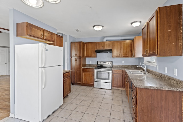 kitchen featuring light tile patterned flooring, under cabinet range hood, a sink, freestanding refrigerator, and stainless steel electric range oven