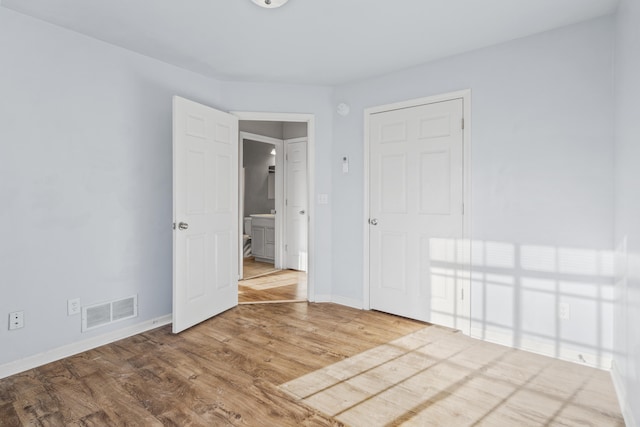 spare room featuring wood finished floors, visible vents, and baseboards