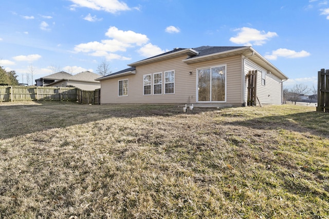 back of property featuring fence and a yard