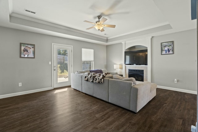 living room featuring a tray ceiling, dark wood-style flooring, and visible vents