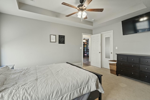 carpeted bedroom featuring a raised ceiling, visible vents, and ceiling fan