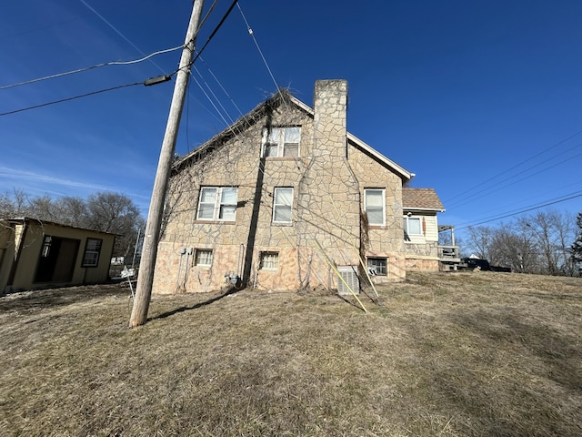 back of property featuring stone siding and a chimney