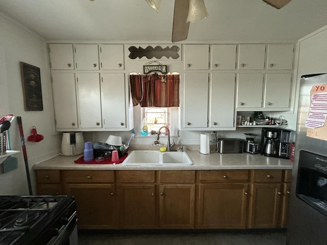 kitchen featuring light countertops, stainless steel refrigerator with ice dispenser, a sink, and white cabinetry