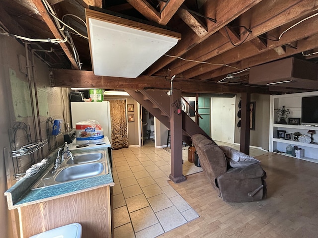 finished basement featuring light wood-type flooring, freestanding refrigerator, a sink, and stairway