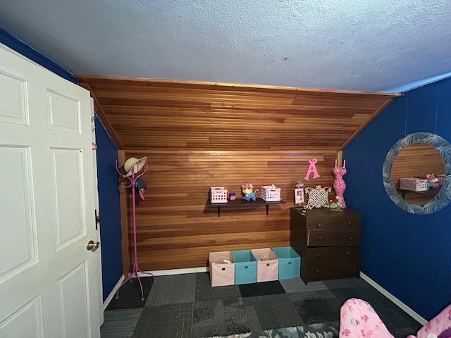 unfurnished bedroom featuring a textured ceiling, wood walls, and baseboards