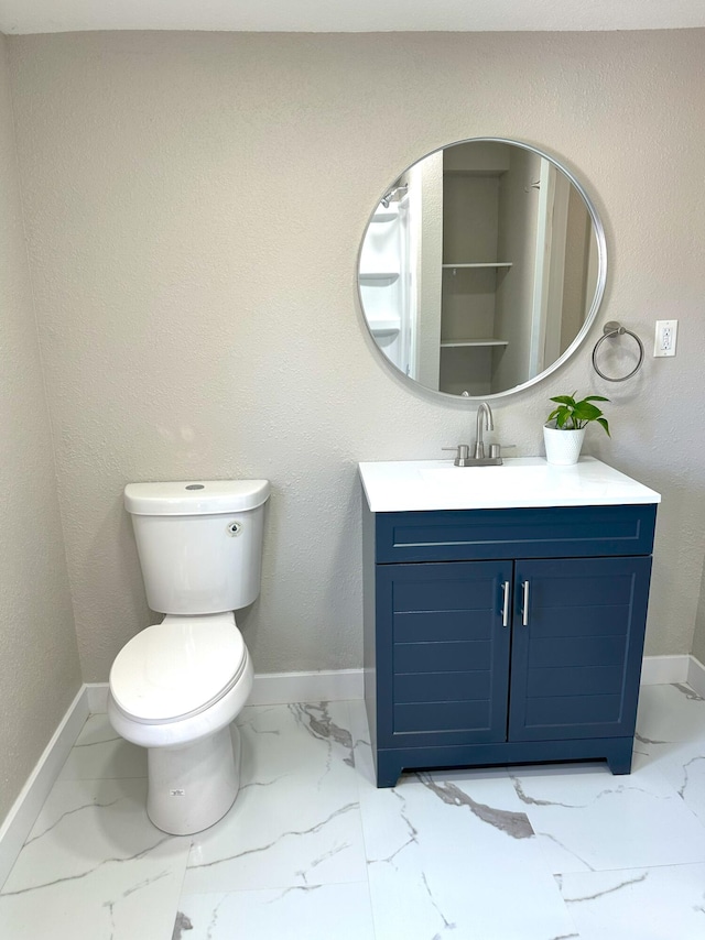 bathroom with marble finish floor, toilet, vanity, and baseboards