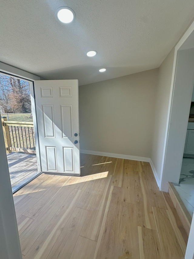 interior space with light wood finished floors, baseboards, a textured ceiling, and recessed lighting