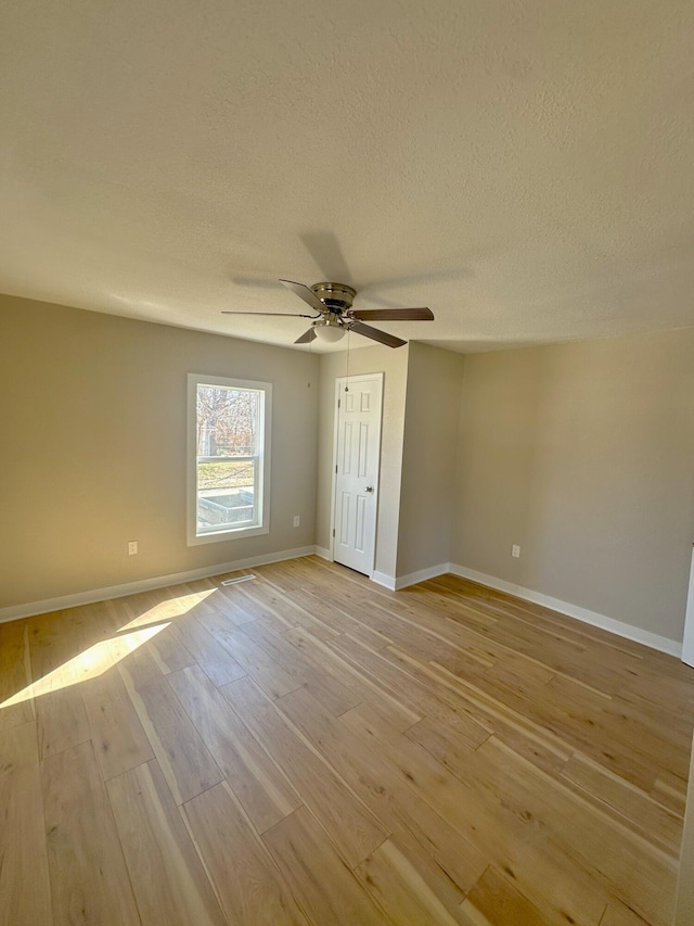 unfurnished bedroom with a textured ceiling, ceiling fan, light wood-type flooring, and baseboards