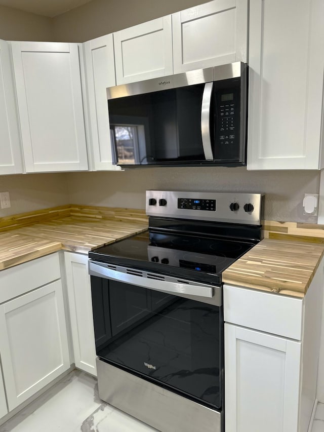 kitchen featuring white cabinetry, butcher block counters, appliances with stainless steel finishes, and marble finish floor