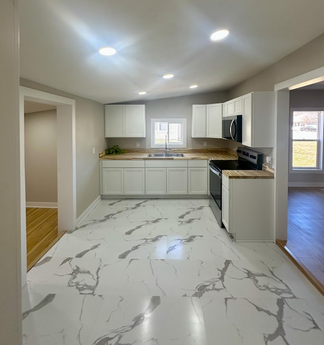 kitchen with a wealth of natural light, baseboards, stainless steel electric range oven, and a sink