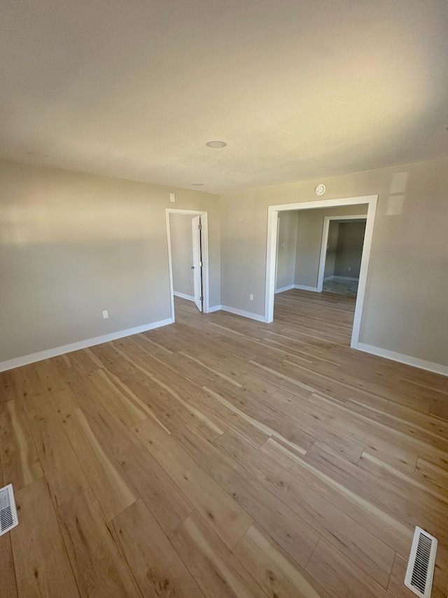 empty room featuring baseboards, visible vents, and light wood finished floors