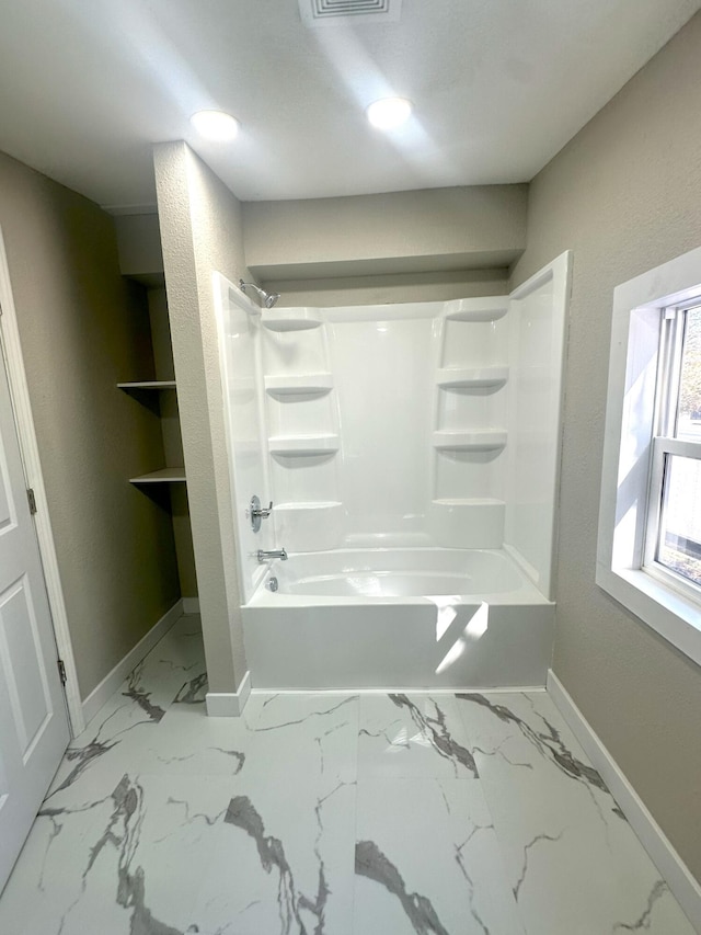 bathroom featuring marble finish floor, shower / tub combination, and baseboards