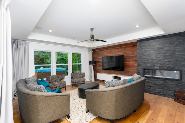 living room with a fireplace, recessed lighting, a raised ceiling, a ceiling fan, and hardwood / wood-style flooring