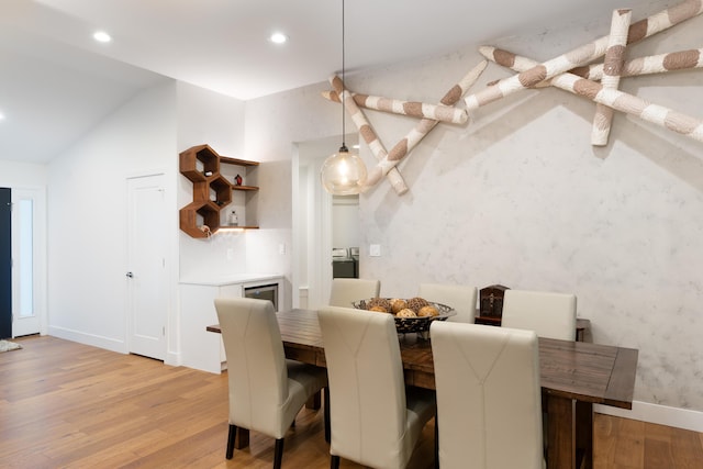 dining space with recessed lighting, vaulted ceiling, a bar, and light wood finished floors