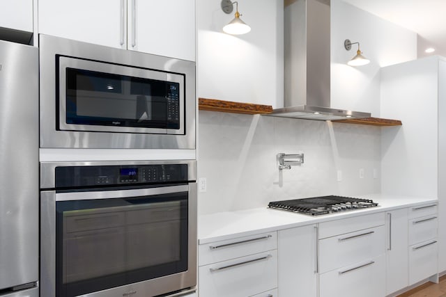 kitchen with modern cabinets, stainless steel appliances, light countertops, white cabinetry, and exhaust hood