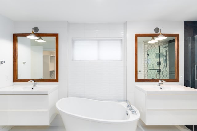 bathroom with a sink, a stall shower, a soaking tub, and two vanities