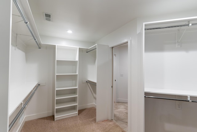 walk in closet with light colored carpet and visible vents