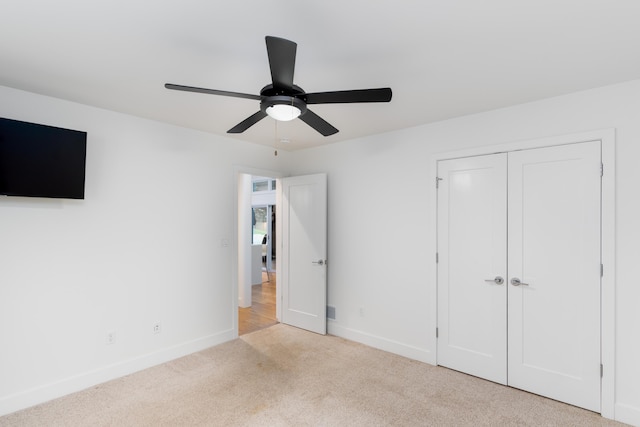 unfurnished bedroom featuring carpet floors, a closet, baseboards, and a ceiling fan