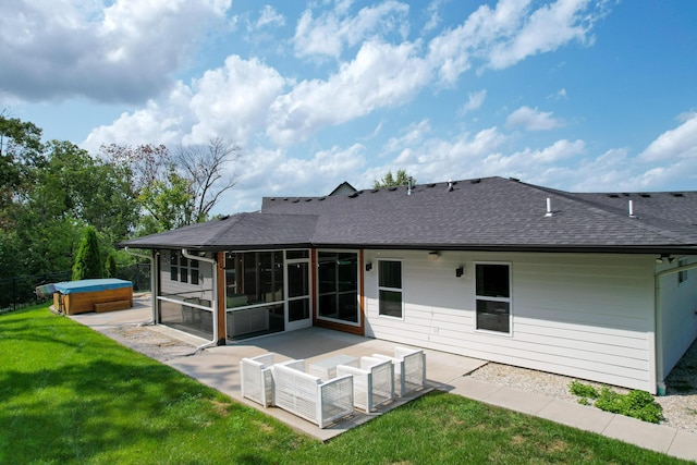 rear view of property featuring a hot tub, a shingled roof, a lawn, a patio, and a sunroom