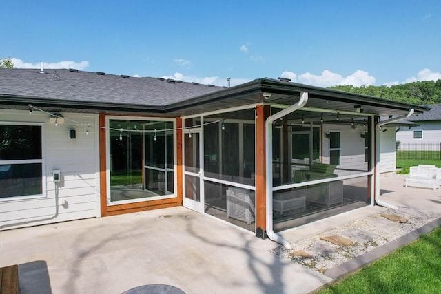 rear view of house with a sunroom, a shingled roof, fence, and a patio