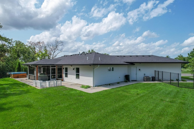 rear view of house with a sunroom, a hot tub, fence, and a lawn