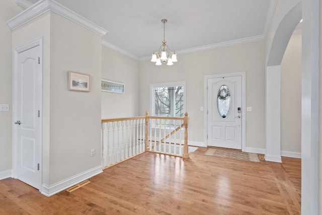 entryway with visible vents, arched walkways, wood finished floors, and ornamental molding