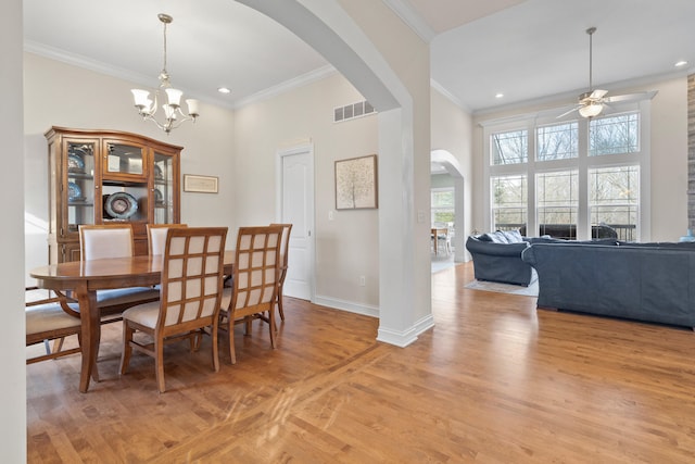 dining space featuring light wood finished floors, baseboards, visible vents, arched walkways, and crown molding