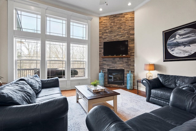 living area featuring light wood finished floors, a fireplace, a wealth of natural light, and crown molding