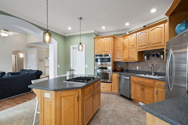 kitchen with arched walkways, dark countertops, backsplash, appliances with stainless steel finishes, and a sink