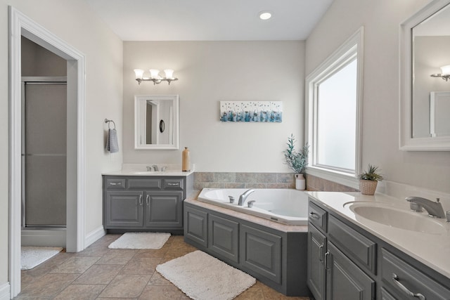 full bath featuring a garden tub, a stall shower, two vanities, and a sink