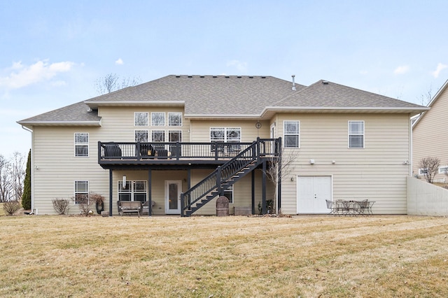 back of property featuring a shingled roof, stairway, a wooden deck, and a lawn