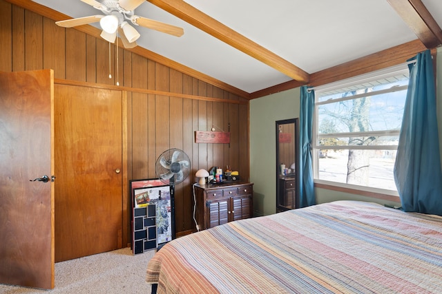 bedroom featuring wooden walls, lofted ceiling with beams, and carpet