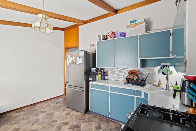 kitchen featuring beam ceiling, blue cabinets, freestanding refrigerator, and stone finish flooring