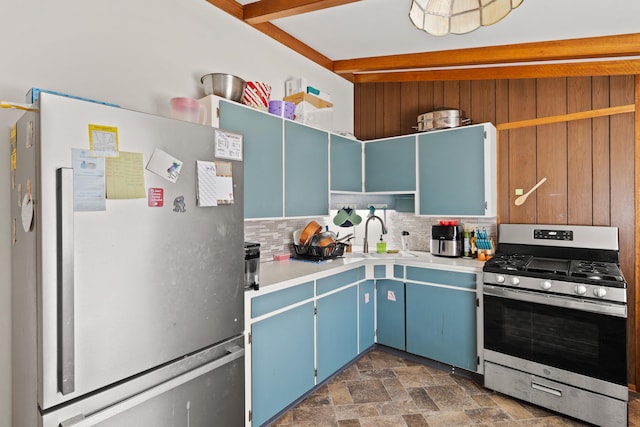 kitchen featuring blue cabinets, stainless steel gas stove, a sink, open shelves, and freestanding refrigerator