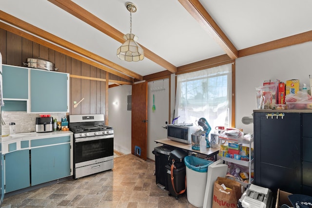 kitchen featuring beam ceiling, light countertops, appliances with stainless steel finishes, stone finish flooring, and backsplash