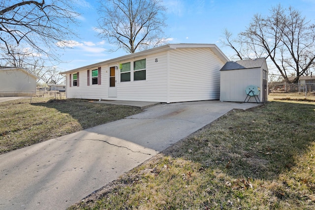 single story home with an outbuilding, a storage shed, a front yard, and fence