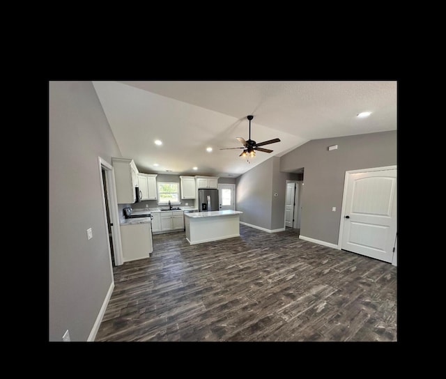 kitchen with a center island, lofted ceiling, appliances with stainless steel finishes, dark wood-type flooring, and open floor plan